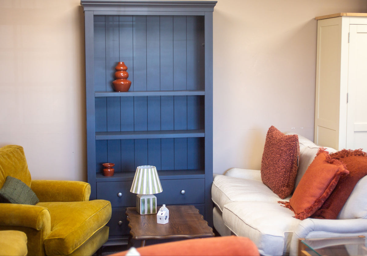 Living room with a yellow armchair, blue bookshelf, and white sofa with red cushions.